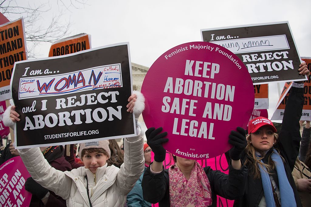 Pro-choice and pro-life protesters hold up opposing signs at a rally.