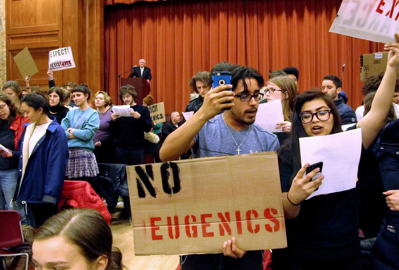 Students protest at Middlebury College. One student holds a cardboard sign that reads 'no eugenics'